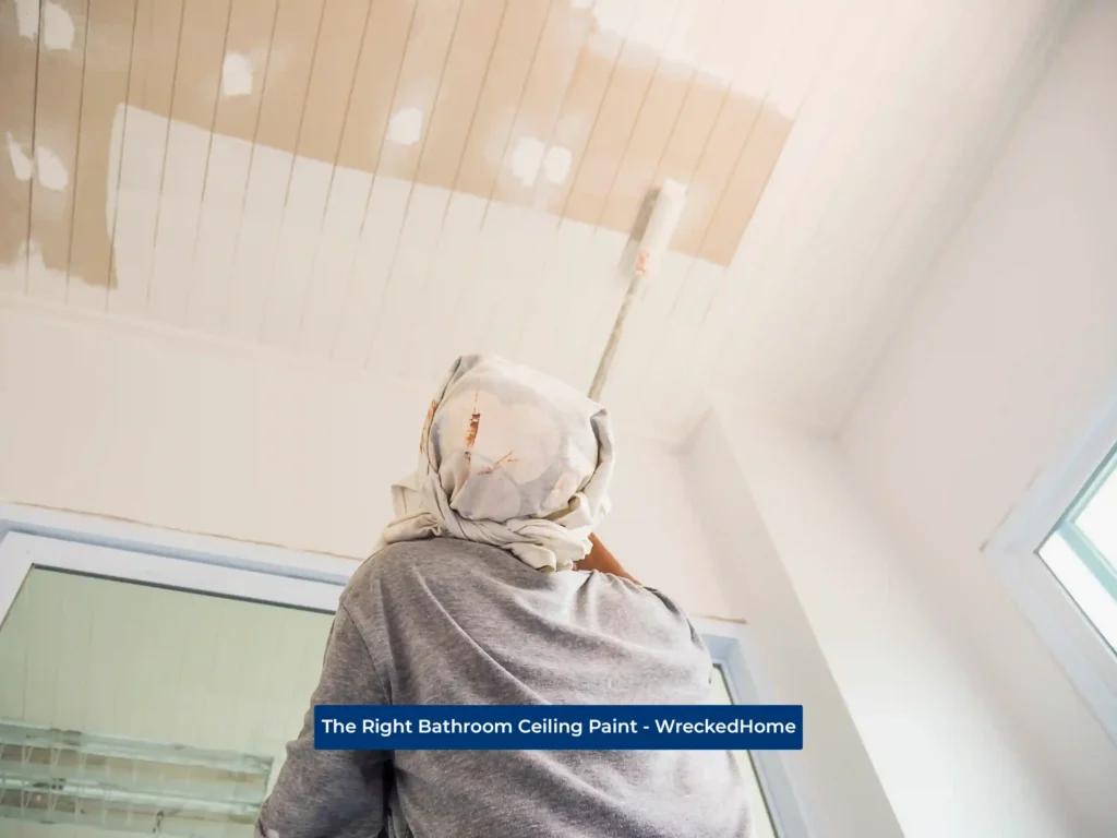 Worker painting bathroom ceiling