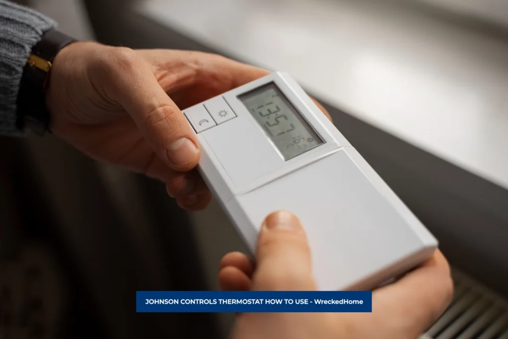 MAN ADJUSTING JOHNSON CONTROLS THERMOSTAT.